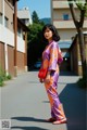 A woman in a purple and orange kimono is walking down the street.