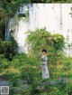 A woman standing in the middle of a lush green forest.