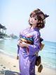 A woman in a purple kimono standing on a beach.