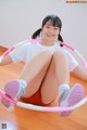 A young woman sitting on the floor with a hula hoop.