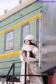 A woman in a white coat and hat standing on a train.