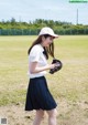 A woman in a white shirt and black skirt holding a baseball glove.