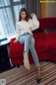 A woman sitting on a red couch in a hotel room.