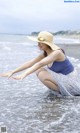 A woman in a straw hat is sitting in the water.