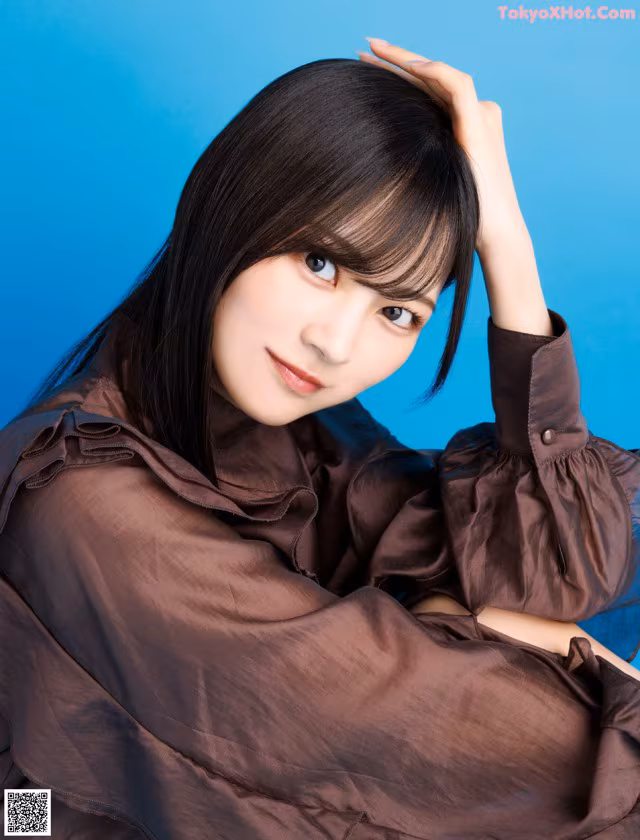 A woman in a brown shirt is posing for a picture.