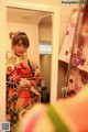 A woman in a kimono standing in front of a mirror.