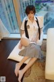 A woman in a school uniform sitting on a pillow.