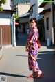 A woman in a purple kimono is walking down the street.