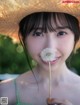 A young girl in a straw hat holding a dandelion.