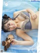 A woman laying on a bed holding a teddy bear.