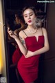 A woman in a red dress smoking a cigarette.