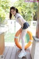 A woman in a school uniform posing next to a swimming pool.